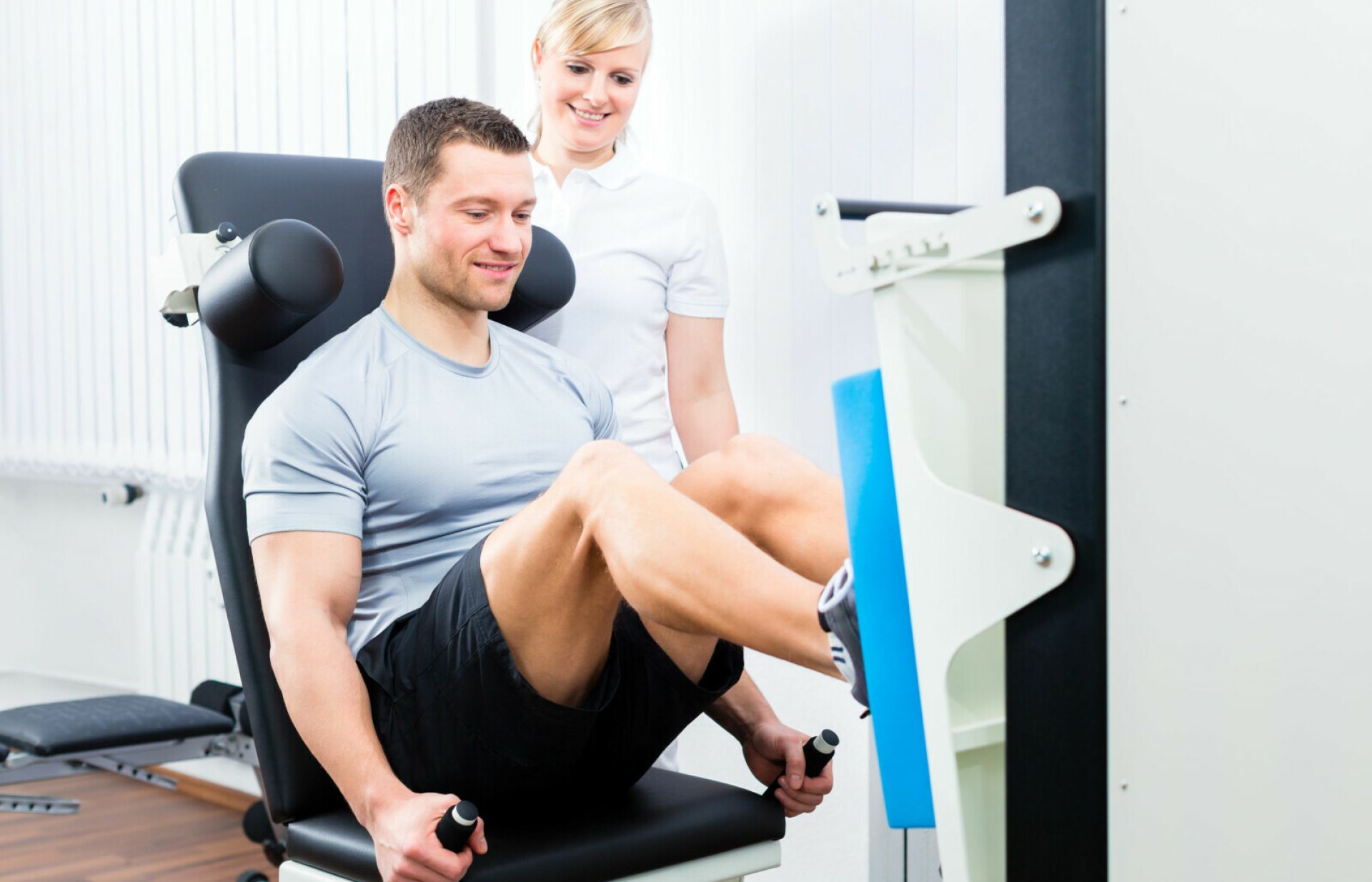 Man traint op fitnessapparaat zijn beenspieren onder begeleiding van arts