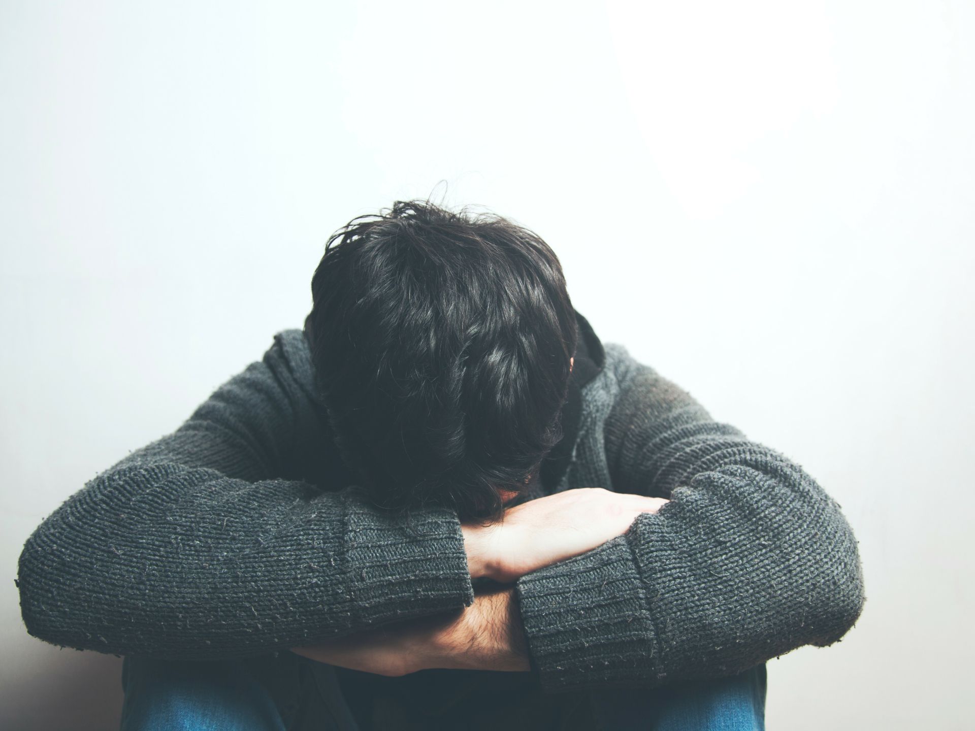Jongen zit bedroefd met zijn hoofd tussen zijn benen