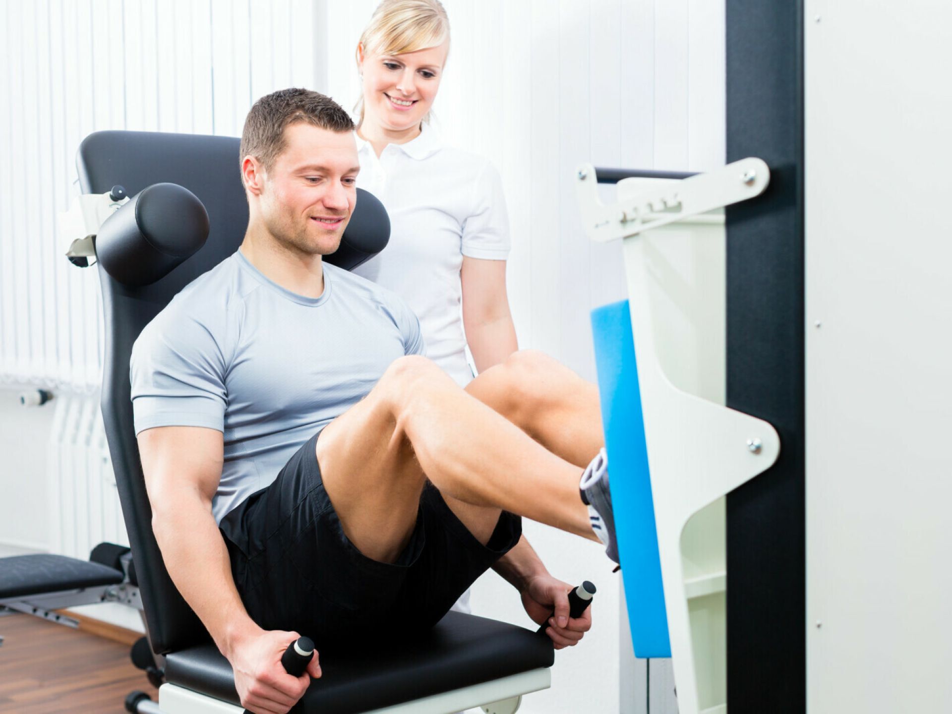 Man traint op fitnessapparaat zijn beenspieren onder begeleiding van arts